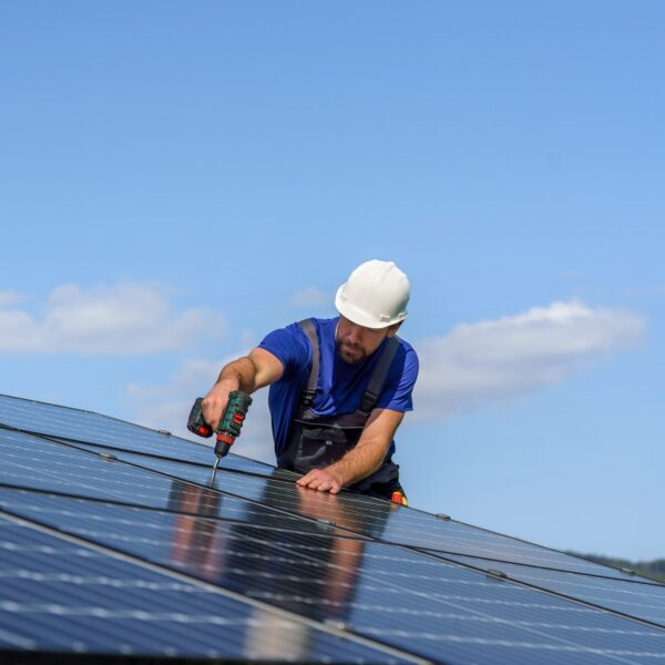 Man worker installing solar photovoltaic panels on roof, alternative energy concept.